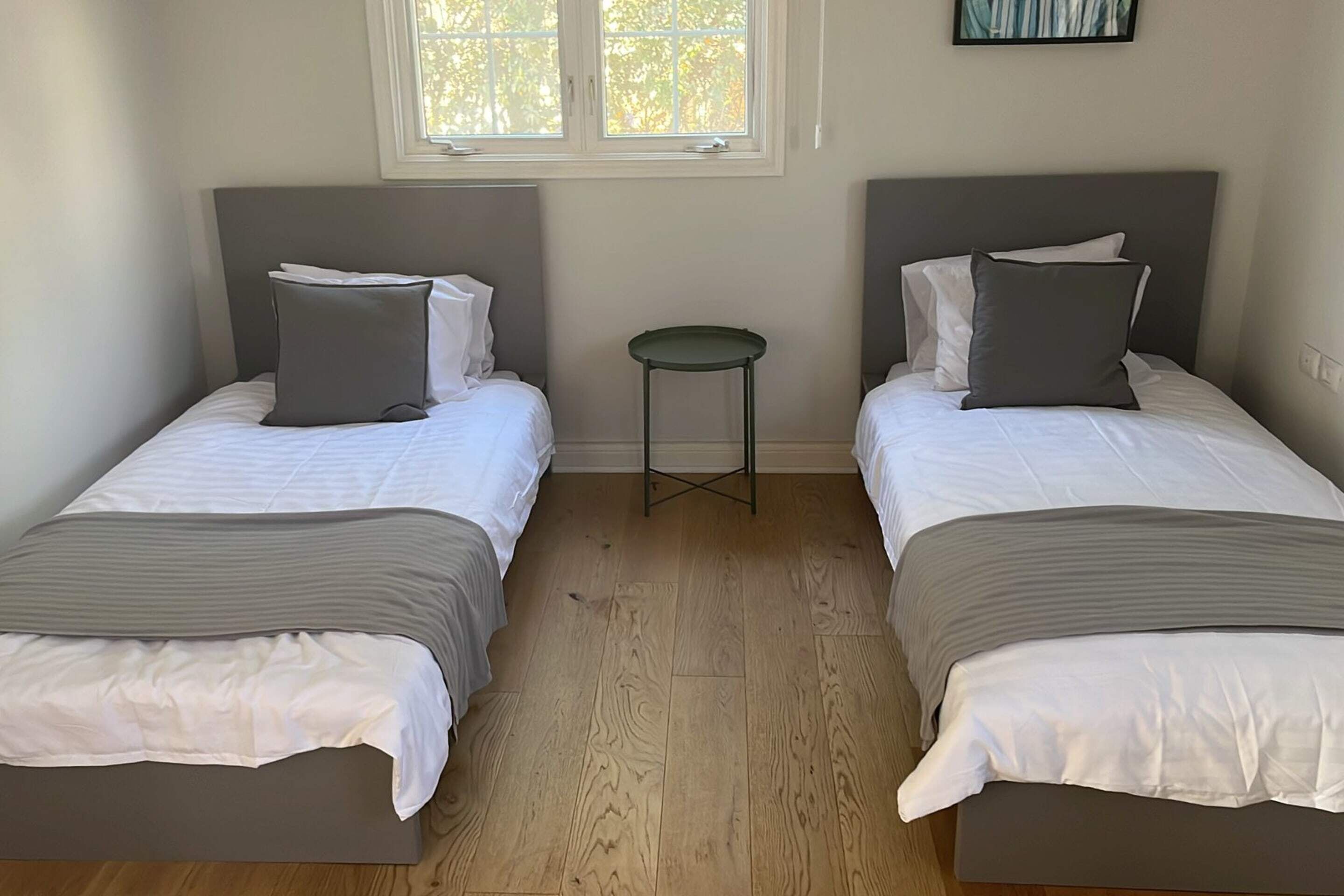 Une chambre avec deux lits, une petite table et une fenêtre.