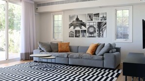A modern living room with a grey sofa, a black and white checkered rug, and a wall with black and white photographs. - Gorgeous Mansion by Caesarea's Greatest Beach-hosted by Sweetstay (Hof HaCarmel)