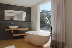 A modern bathroom with a freestanding bathtub, a wooden vanity, and a large mirror.