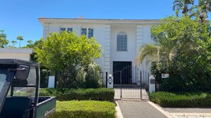 A white building with a gated entrance, surrounded by greenery and palm trees. - Gorgeous Mansion by Caesarea's Greatest Beach-hosted by Sweetstay (Hof HaCarmel)
