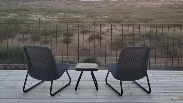 A balcony with two chairs and a small table, overlooking a beach with dunes. - Gorgeous Mansion by Caesarea's Greatest Beach-hosted by Sweetstay (Hof HaCarmel)