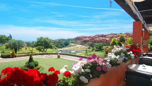 Una terraza con vistas a un campo de golf y un pueblo a lo lejos.