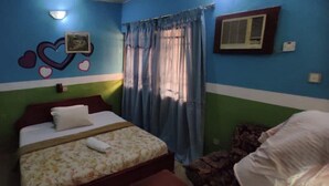 A bedroom with a bed, a pillow, a wall with a heart design, a window with curtains, and an air conditioning unit. - Townhall Hotel & Suites (Lagos)