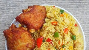 A plate of fried chicken and rice with vegetables. - Townhall Hotel & Suites (Lagos)