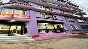 Un edificio de varios pisos con fachada morada, un letrero de restaurante visible y una escalera que lleva a la entrada.