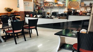 Interior de un restaurante con mostrador, sillas y un panel de menú.