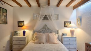 Un dormitorio con una cama con dosel, dos mesitas de noche con lámparas y un tocador con lámpara.