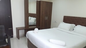 A neatly made bed with white linens, a wooden headboard, and a large mirror above it. - CNR Residency Madanapalle (Madanapalle)