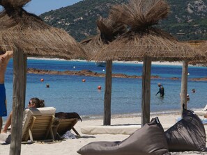 A beach with thatched umbrellas, wooden chairs, and a clear view of the sea. - Sunset Villa with Bay View (Albitreccia   /  Porticcio)