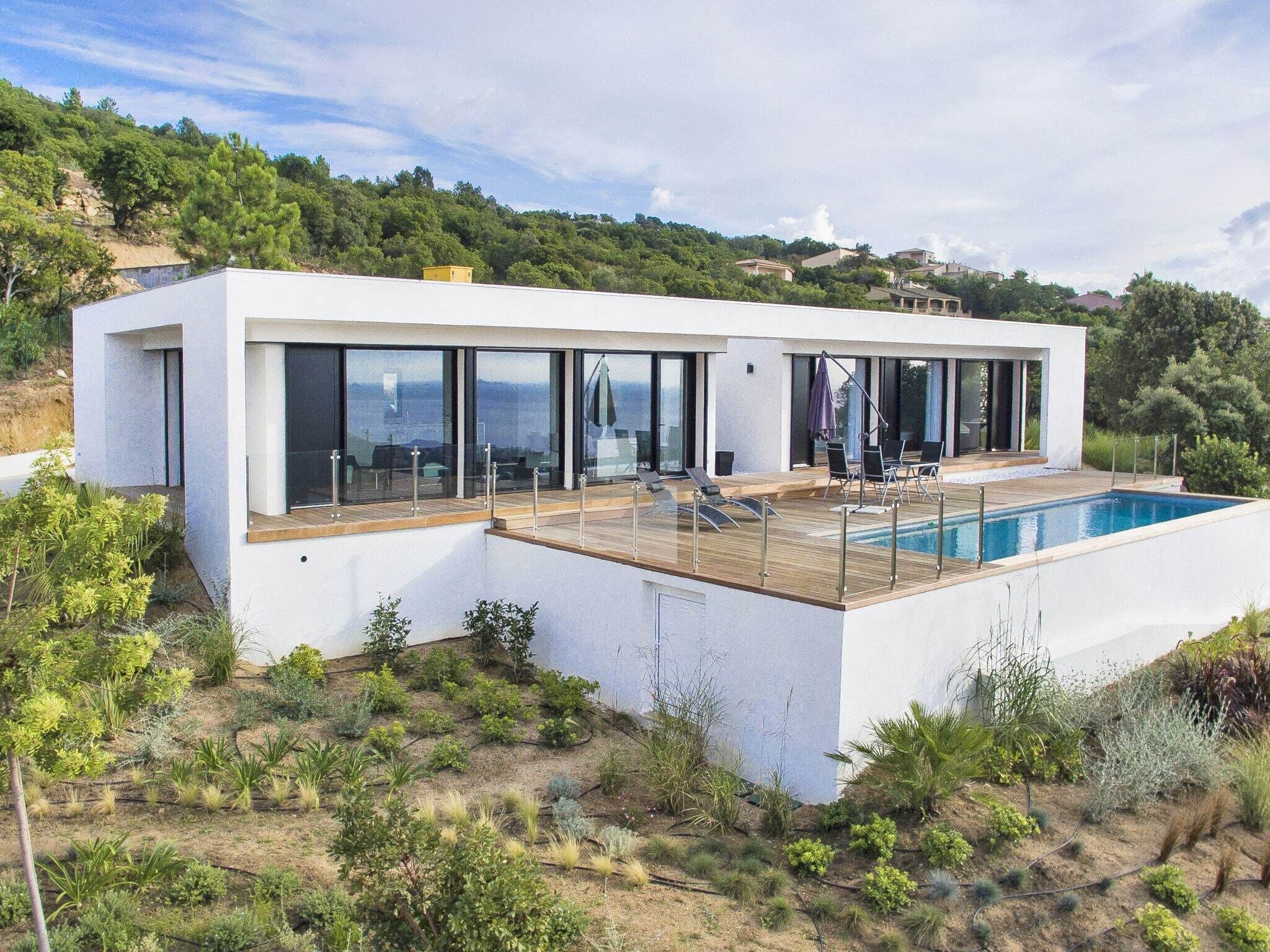 Una casa moderna con piscina, ventanas amplias y terraza.