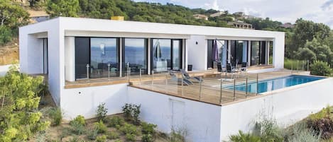 A modern house with a swimming pool, large windows, and a deck.