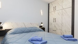 A modern bedroom with a large bed, a nightstand, a lamp, and a wardrobe with a marble finish. - Cosy apartment for 3 guests with WIFI, A/C, TV and balcony (Lloret De Mar)