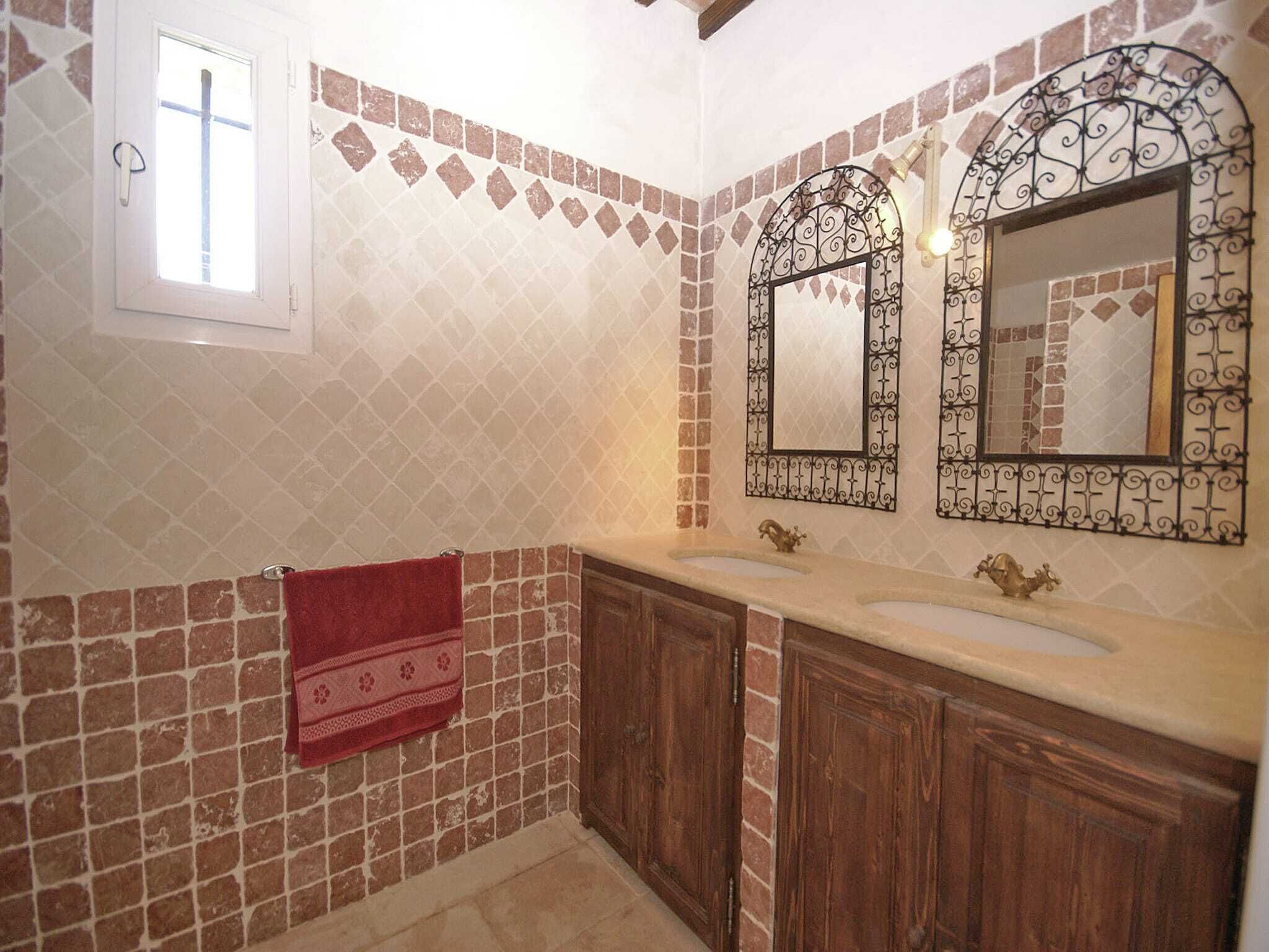 Un bagno con due lavabi, un asciugamano rosso e specchi decorativi.