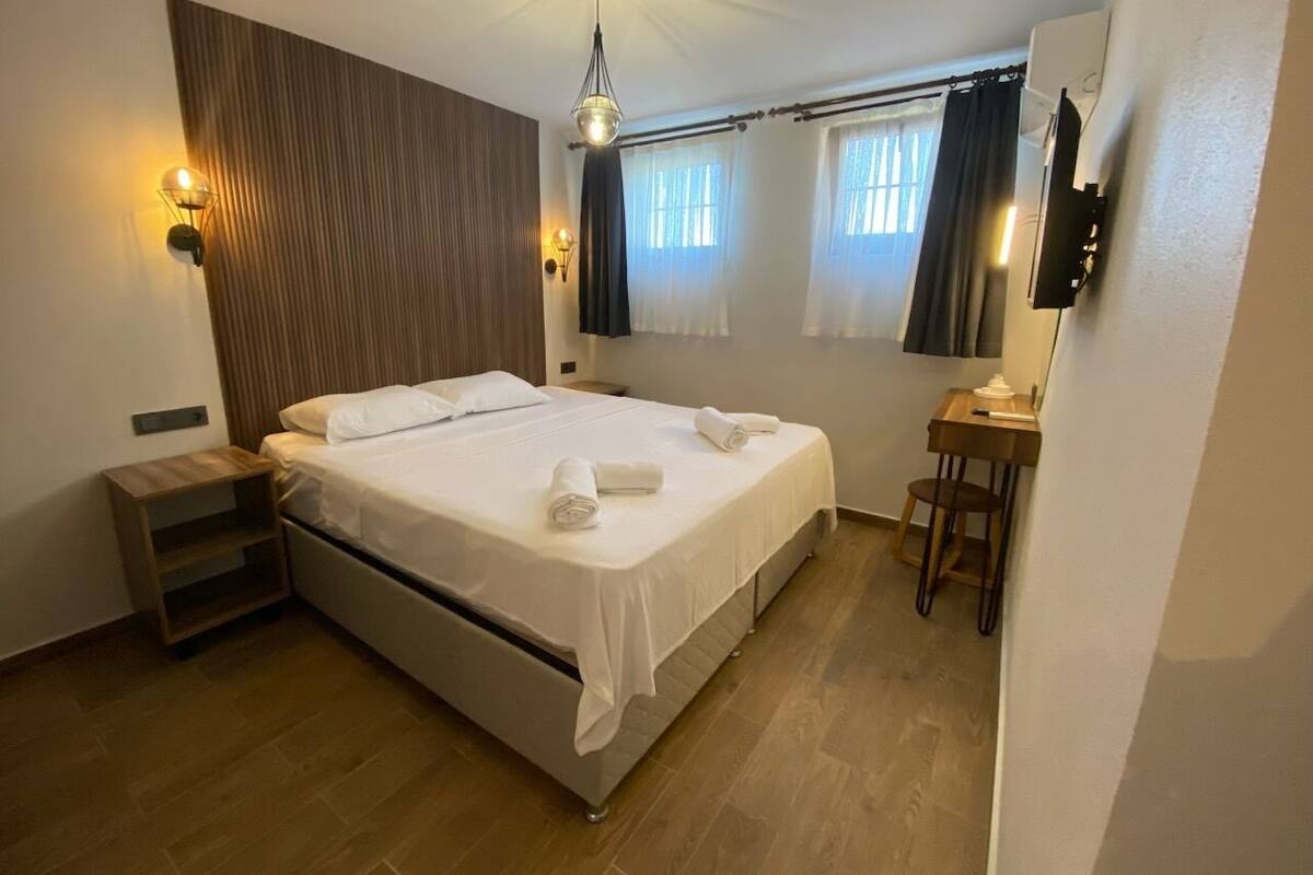 A bedroom with a bed, bedside tables, a desk, and a chair.