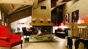 A cozy living room with a stone fireplace, wooden beams, and a red armchair. - Holiday home in Saint-Martin-de-Belleville (Saint-Martin-de-Belleville)