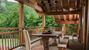 A wooden deck with a table and chairs, surrounded by a railing, overlooking a lush green landscape. - Holiday home in Saint-Martin-de-Belleville (Saint-Martin-de-Belleville)