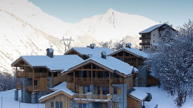 A multi-story lodge with wooden balconies and stone walls, surrounded by snow-covered mountains. - Holiday home in Saint-Martin-de-Belleville (Saint-Martin-de-Belleville)