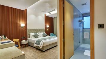 A modern hotel room with a bed, bedside table, and a bathroom visible through an open door.