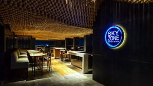 A modern interior with a unique ceiling design, a bar area, and a seating arrangement. - Regenta Place Raysons Kolhapur  (Kolhapur)