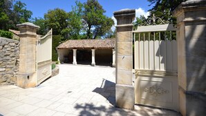 A gated entrance with stone pillars and a tiled roof structure in the background. - Villa in Provence near Vaison-la-Romaine (Vaison-La-Romaine)