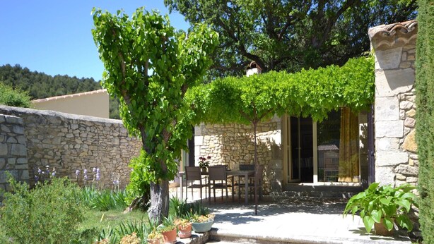 A stone building with a covered patio, outdoor seating, and potted plants. - Villa in Provence near Vaison-la-Romaine (Vaison-La-Romaine)