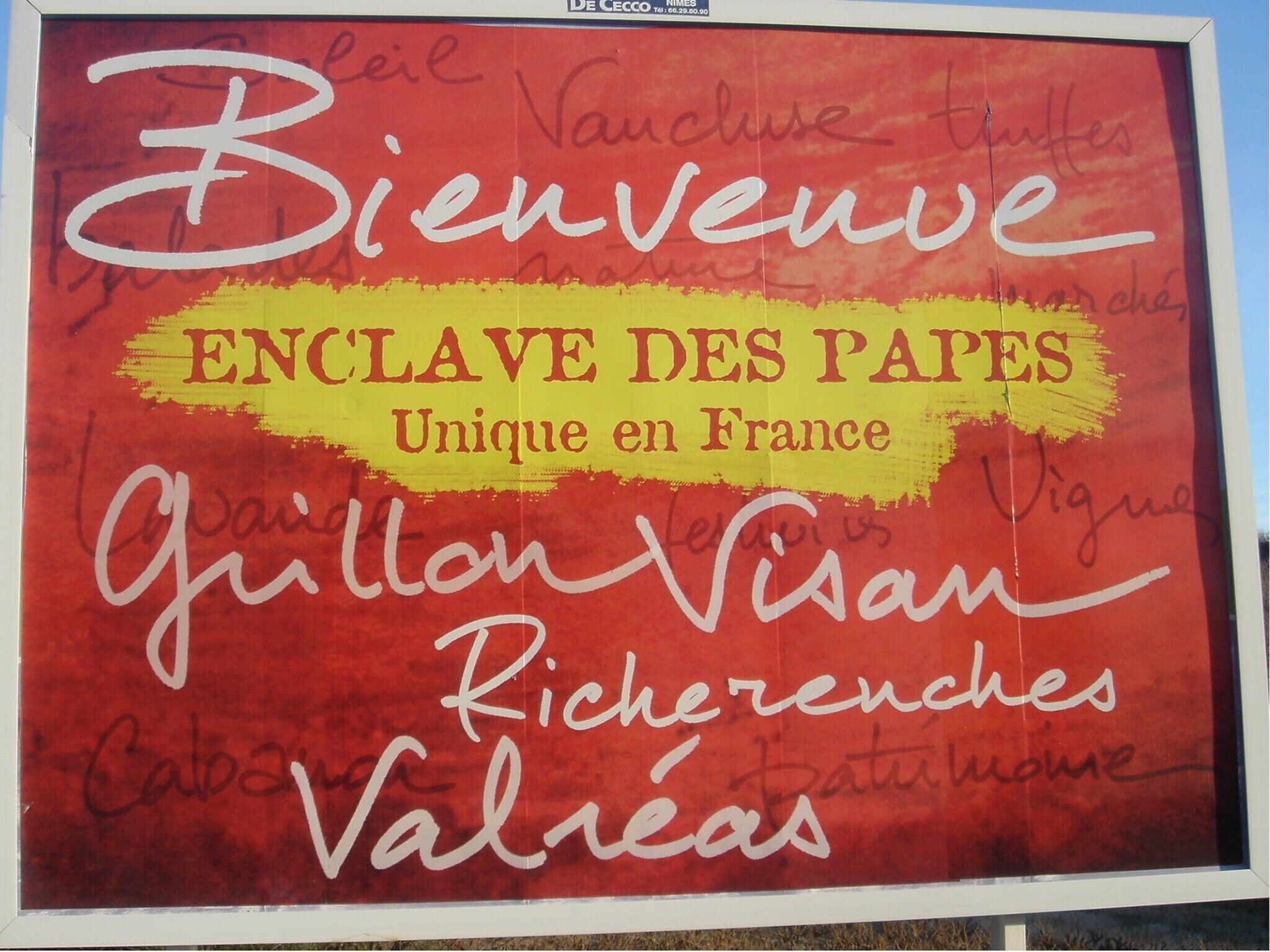 A sign with 'Bienvenue ENCLAVE DES PAPES Unique en France' and several signatures.