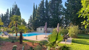A pool area with lounge chairs and umbrellas, surrounded by cacti and palm trees. - Country House in Provence with Garden Access (Valréas)