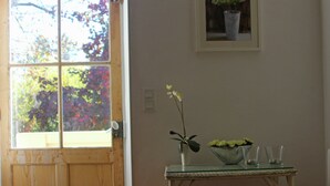 A wooden door with a window, a small table with a bowl and glasses, and a potted plant on the wall. - Country House in Provence with Garden Access (Valréas)