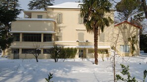 A large, cream-colored building with a snow-covered roof and multiple windows. - Country House in Provence with Garden Access (Valréas)