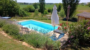 Une piscine avec vue sur un champ verdoyant et des arbres.