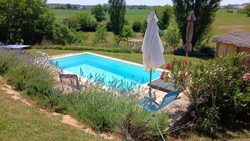 Une piscine avec vue sur un champ verdoyant et des arbres.