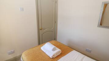 Une chambre d’hôtel avec un lit, une porte, un miroir et une prise électrique.