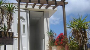 A wooden pergola entrance with a white door, surrounded by potted plants and flowers. - Apartment in Ravdoucha with Sea Views (Voukolies)
