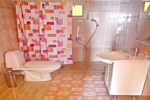 A bathroom with a toilet, shower, sink, and patterned floor. - Apartment in Ravdoucha with Sea Views (Voukolies)