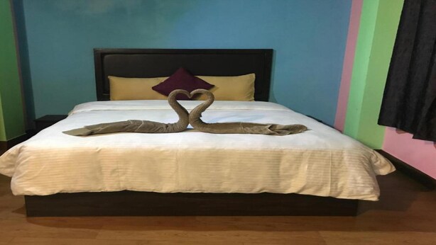 Un lit recouvert d’une courtepointe blanche et agrémenté d’un cygne décoratif fait de serviettes.