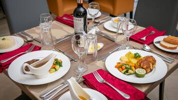 Una mesa de comedor dispuesta con platos de comida, vasos y cubiertos.