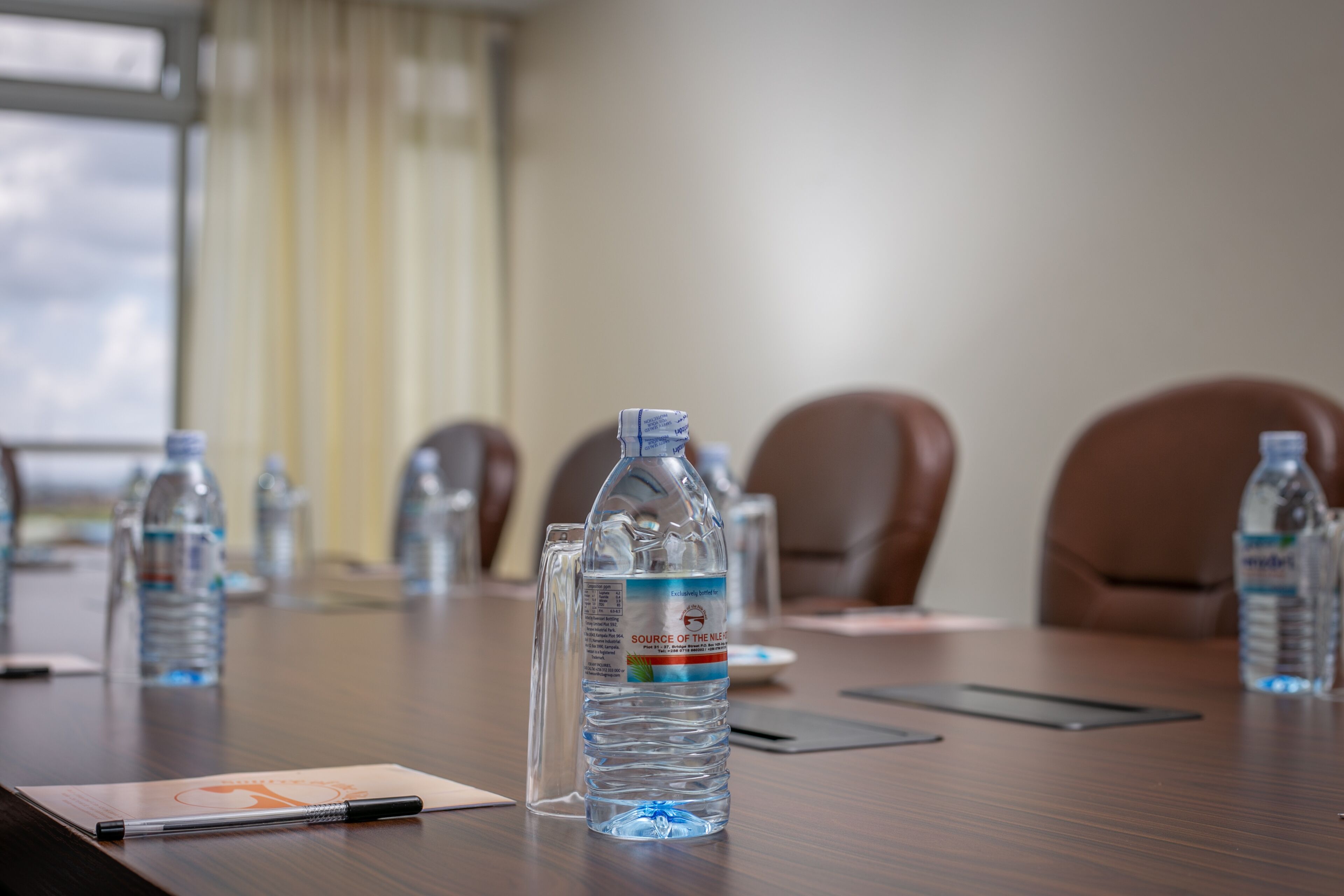 A conference table with water bottles, a notebook, and a pen.