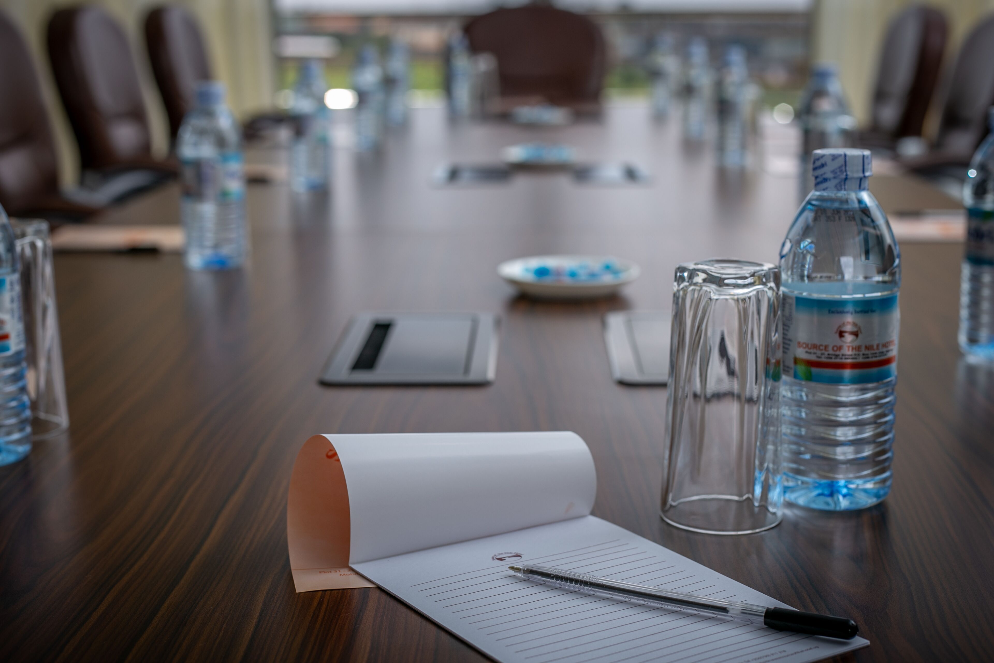 A conference table with water bottles, a laptop, a notepad, and a pen.