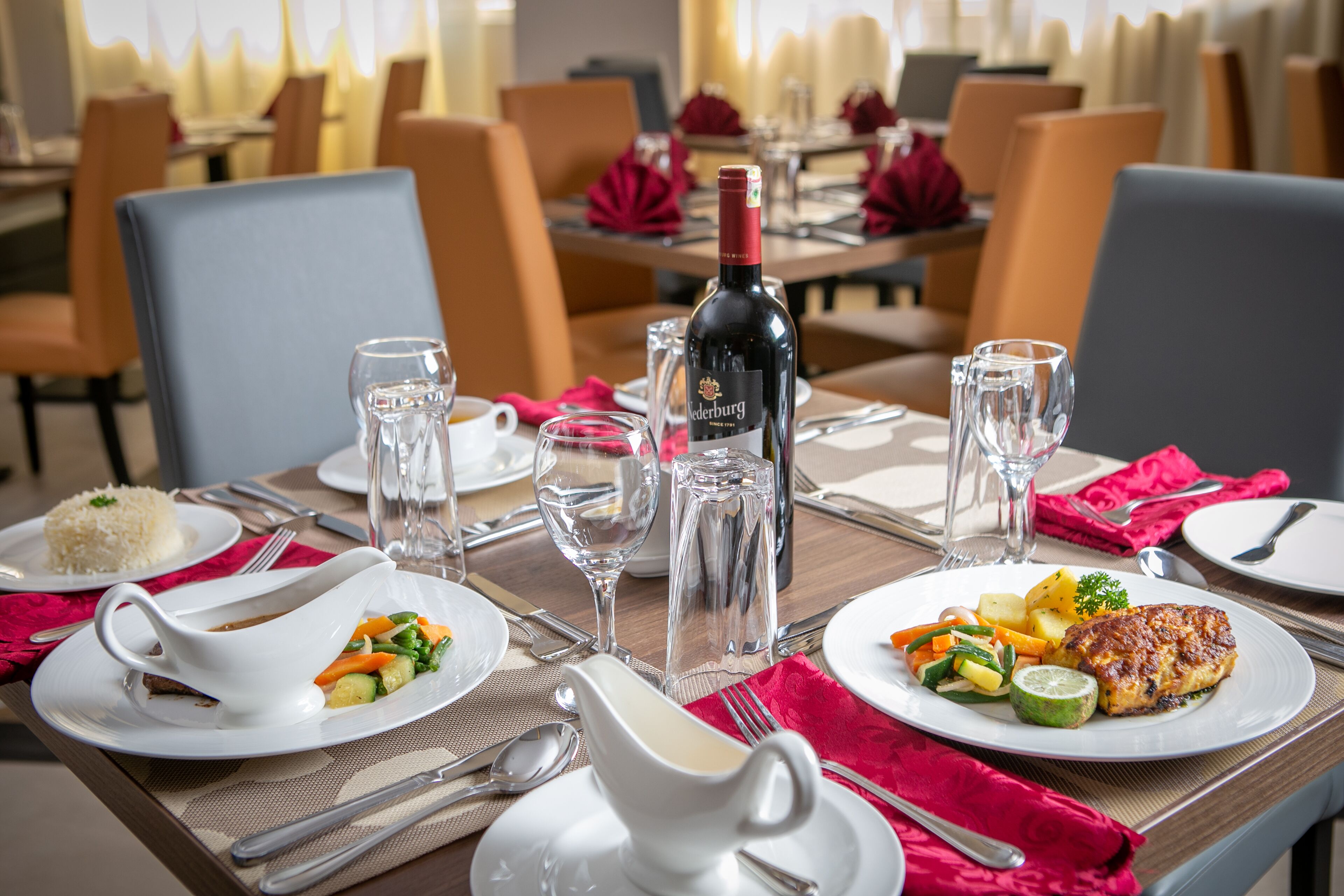 Une table à manger dressée avec des assiettes remplies de nourriture, des verres à vin et des couverts.