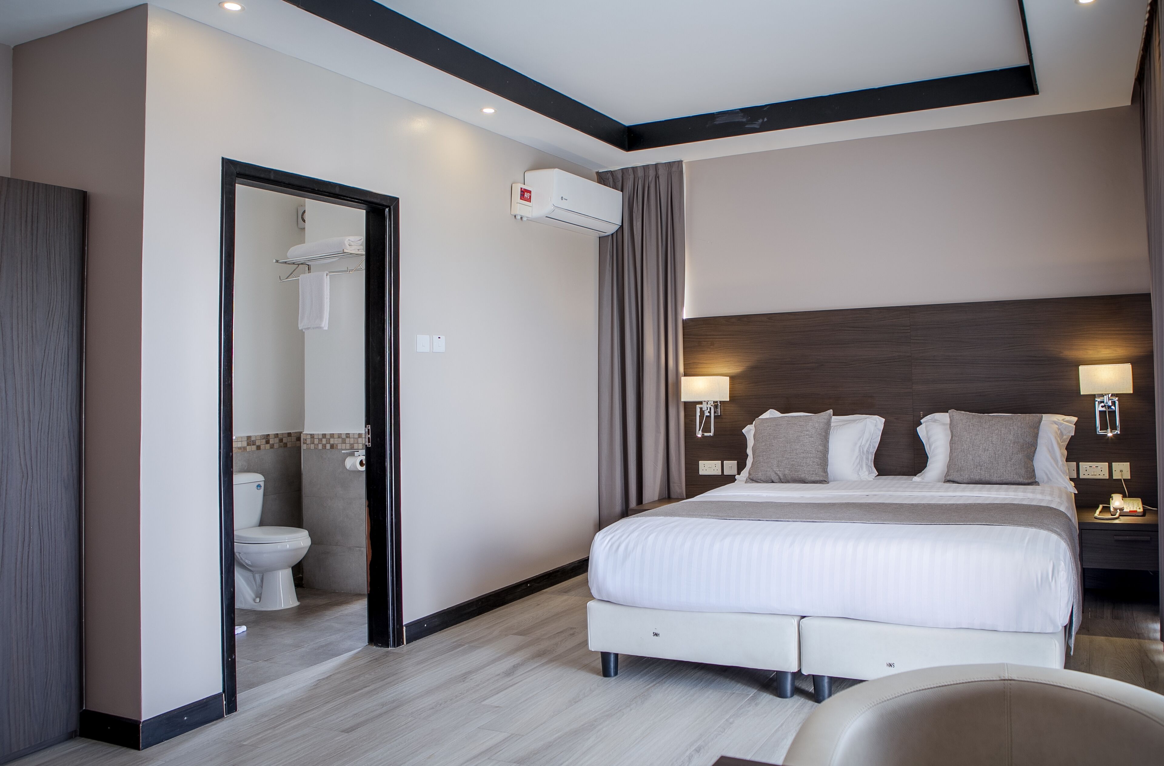 Une chambre d’hôtel moderne avec un grand lit, une salle de bain et une table de chevet avec une lampe.