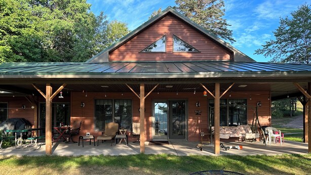 Eine Holzhütte mit verdeckter Veranda, Sitzgelegenheiten im Freien und einem Feuerkorb.