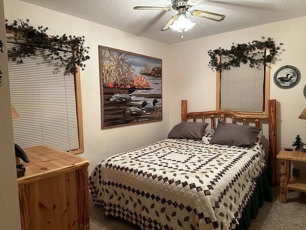 A bedroom with a bed, wooden headboard, and a ceiling fan.