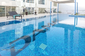 Una piscina con sillas de descanso y una planta en maceta.