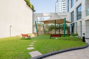 Un patio con dos bancos, una zona con sombra y un camino.