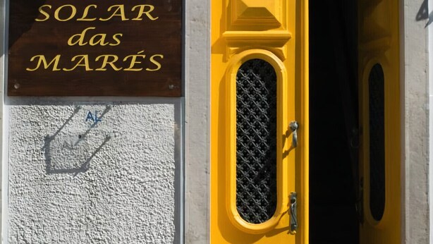 A building entrance with a yellow door, a sign reading "SOLAR das MARES", and a street lamp above.
