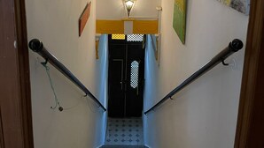 A staircase with a handrail, a light fixture above, and a door at the bottom.