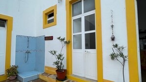 A white building with yellow trim and a tiled shower area.