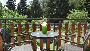 A round table with two wicker chairs, a glass vase with a white flower, and a green vase with a plant. - Apartment in Knin near Knin Fortress (Knin)