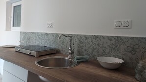 A kitchen with a wooden countertop, stainless steel sink, and a floral backsplash. There are two electrical outlets and a window above the sink. - Dépendance D'une Bastide Provençale (MANOSQUE)