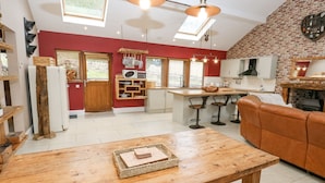 A modern kitchen with a central island, bar stools, and a wooden dining table.